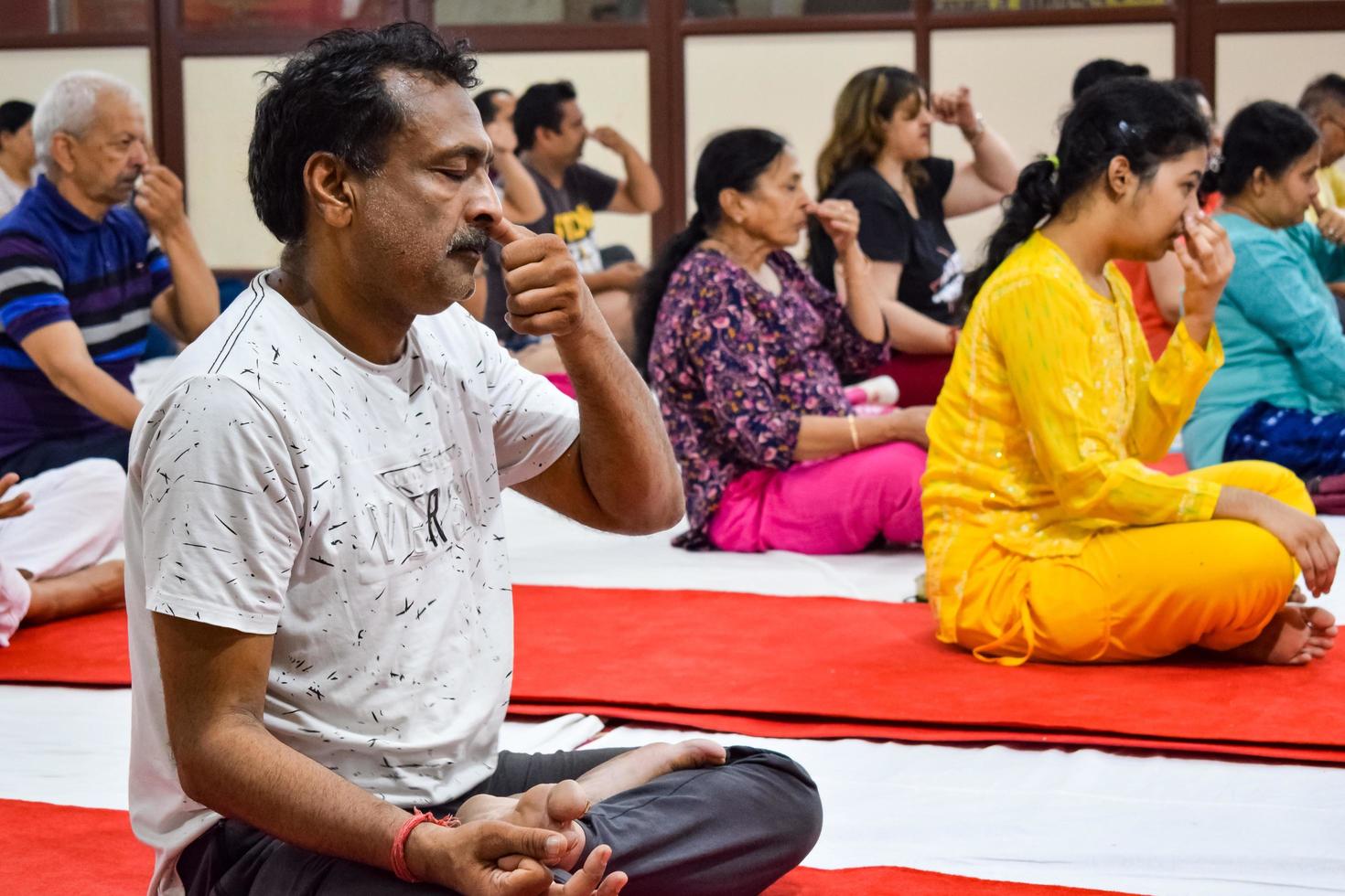 New Delhi, India, June 19 2022 -Group Yoga exercise session for people of different age groups in Balaji Temple, Vivek Vihar, International Yoga Day, Big group of adults attending yoga class in temple photo