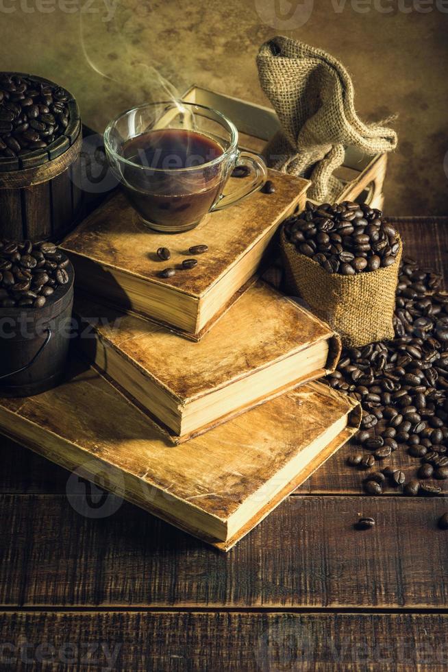 Coffee in cup glass on old books and aged wood floor photo