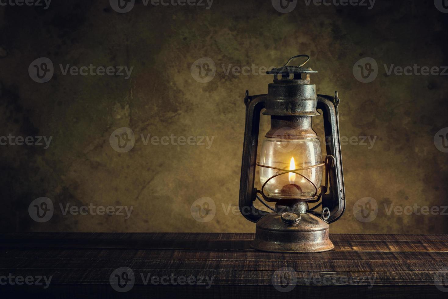 kerosene lamp oil lantern burning with glow soft light on aged wood floor photo