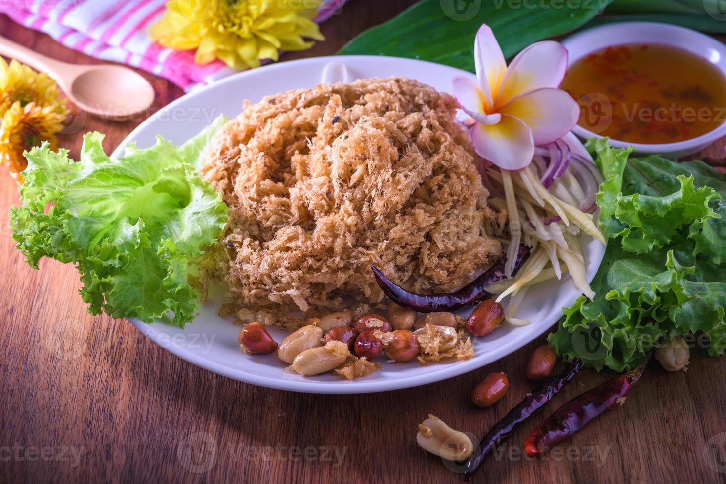 Fluffy spicy catfish with mango sauce Dish dishes on wooden floor Yum Pla-duke Fu photo