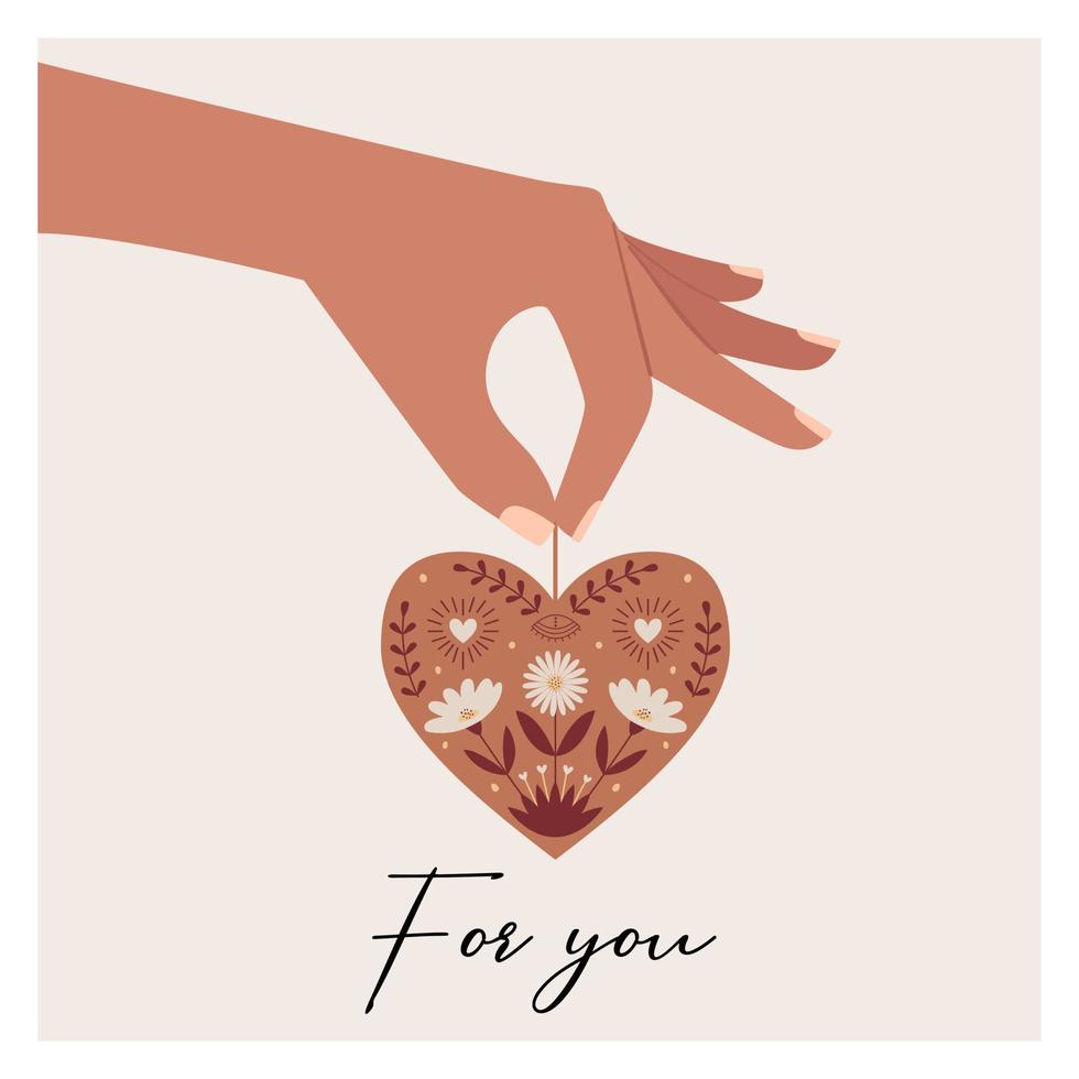 A postcard with a hand holding a hanging heart with flowers, twigs, botanical and boho symbols. Natural colors. Color vector illustration isolated on a white background.