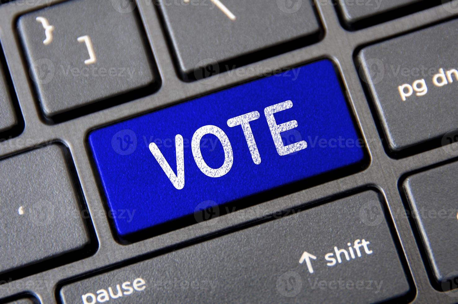 concepto de votación: teclado portátil con botón de votación azul. foto