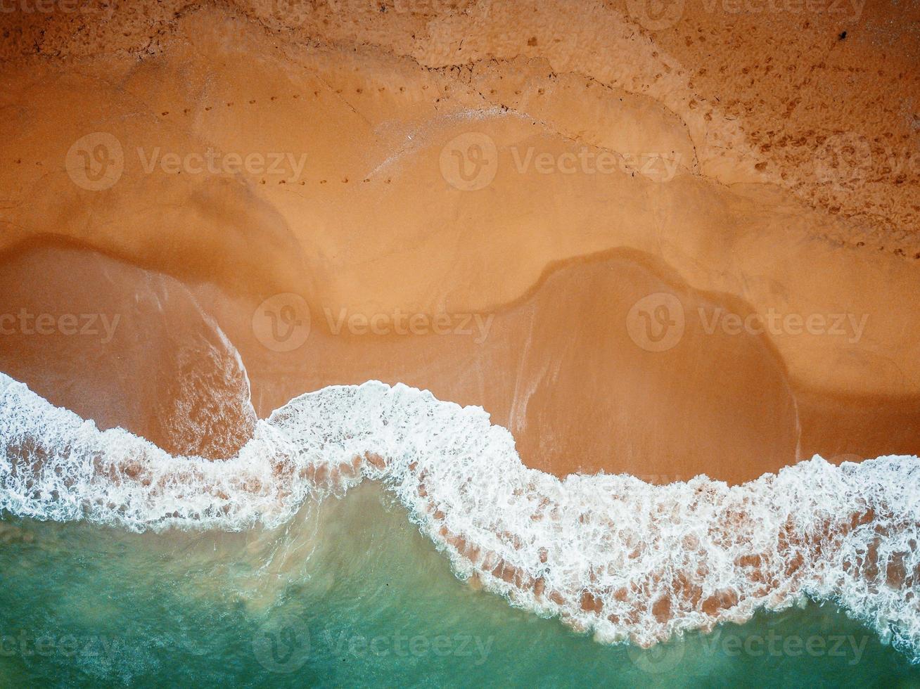 Beach on aerial drone top view with ocean waves reaching shore. photo