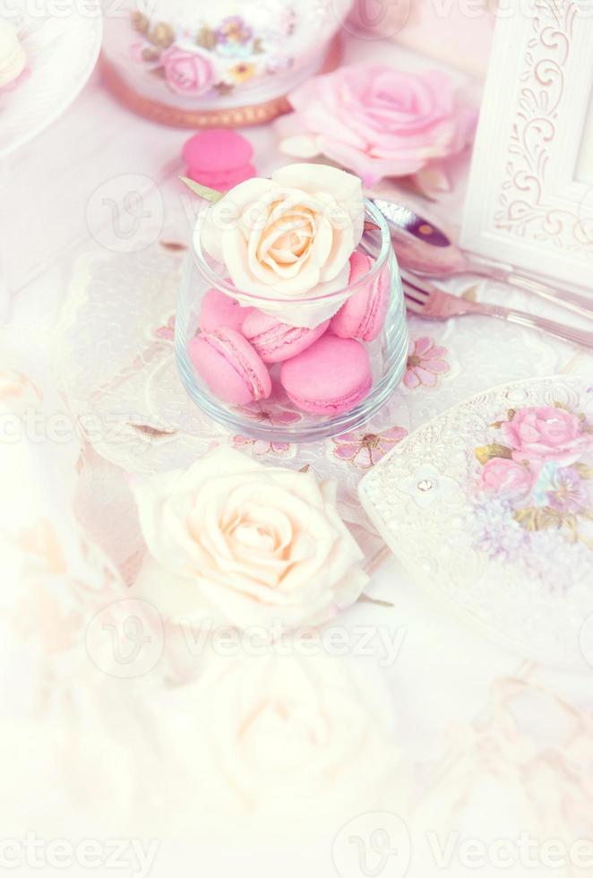 macarons or macaroons in a glass jar with roses with a lovely pink tone photo