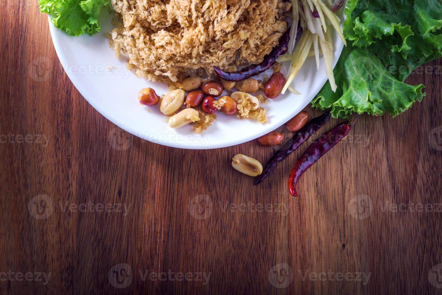 Fluffy spicy catfish with mango sauce Dish dishes on wooden floor Yum Pla-duke Fu photo