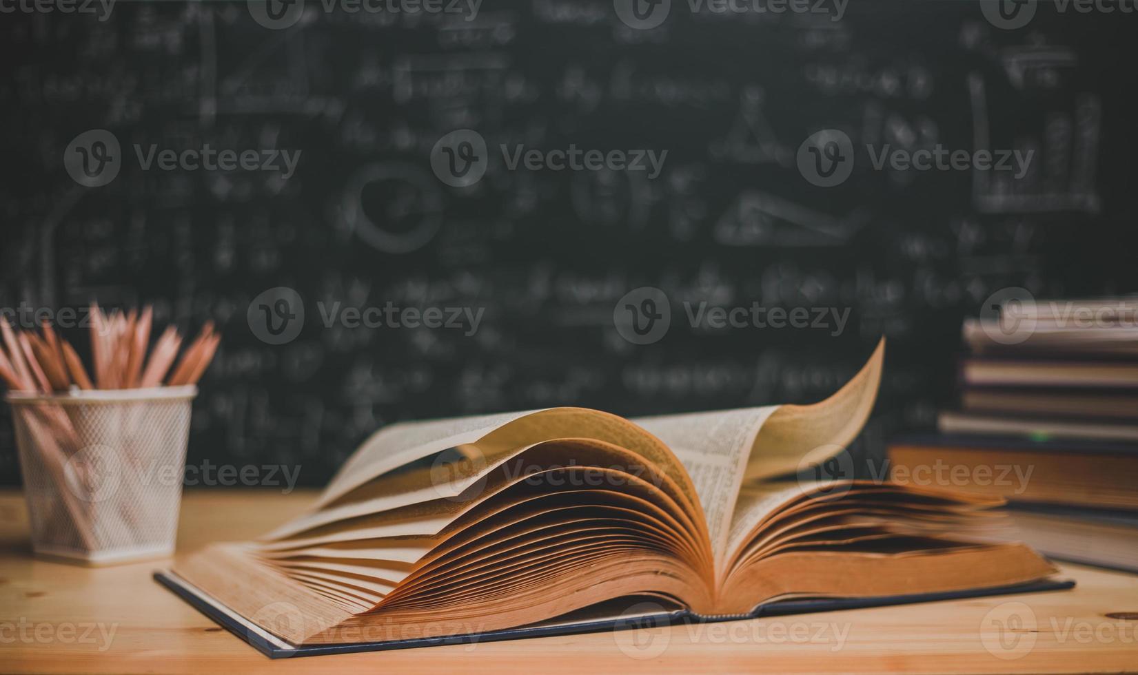 School books on desk formulas and Physics inscription on the blackboard , education concept photo
