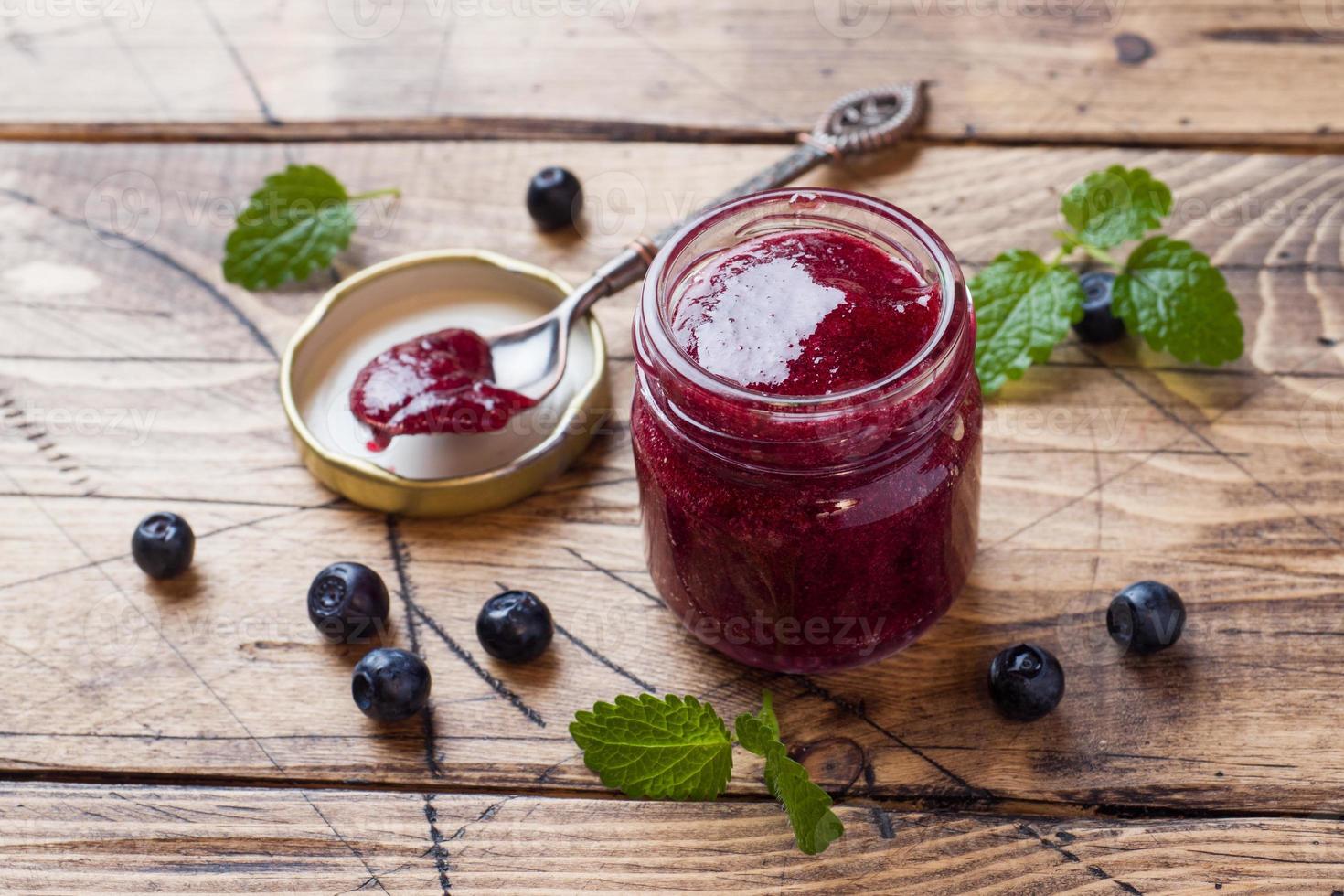 Jar of homemade blueberry jam on a wooden background. photo