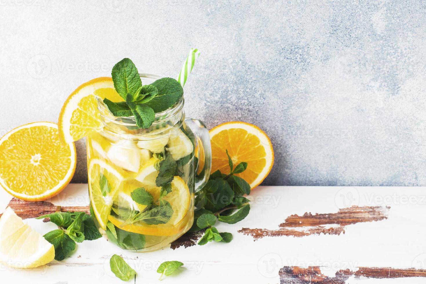 Lemonade drink of soda water, lemon and mint leaves in jar on light background. Copy space photo