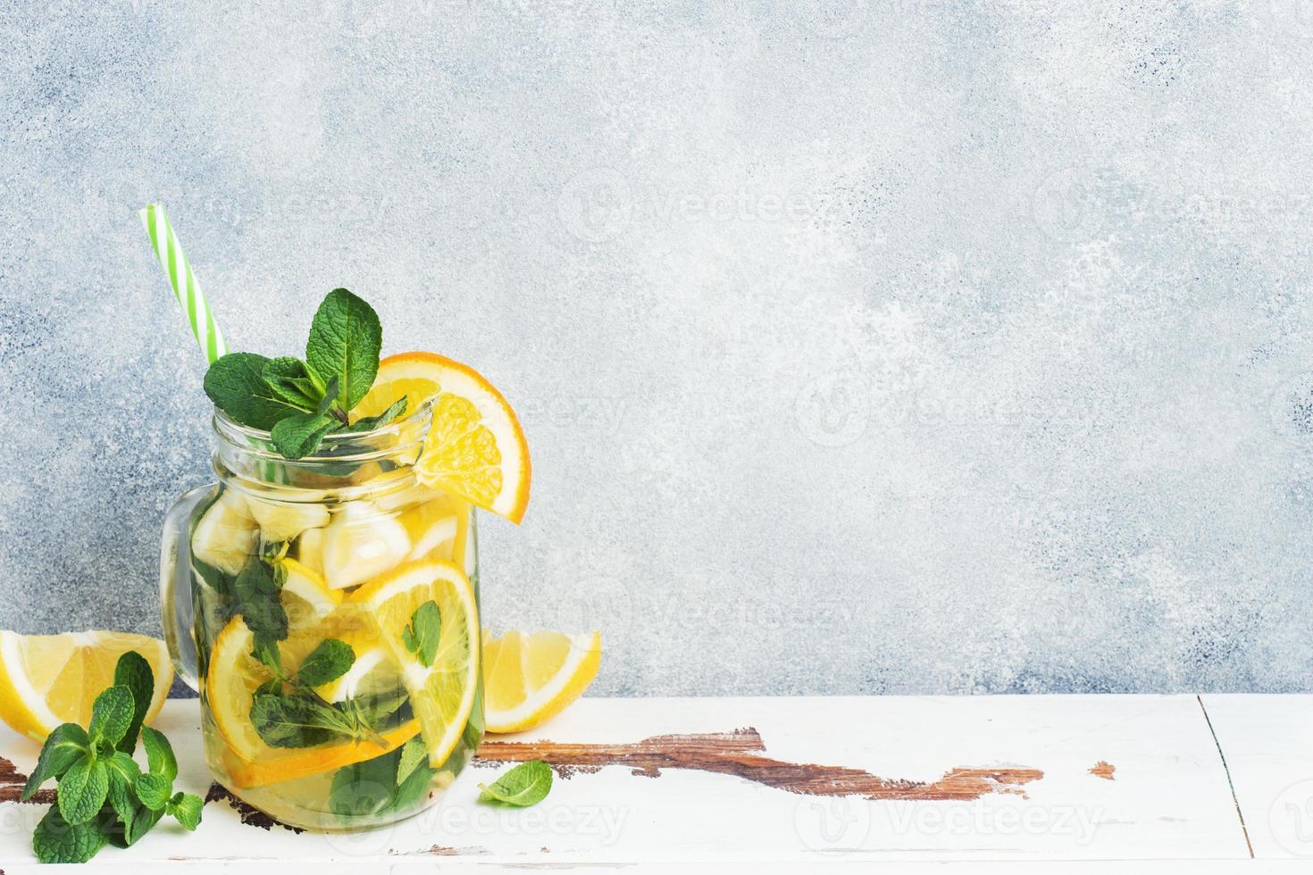 Lemonade drink of soda water, lemon and mint leaves in jar on light background. Copy space photo