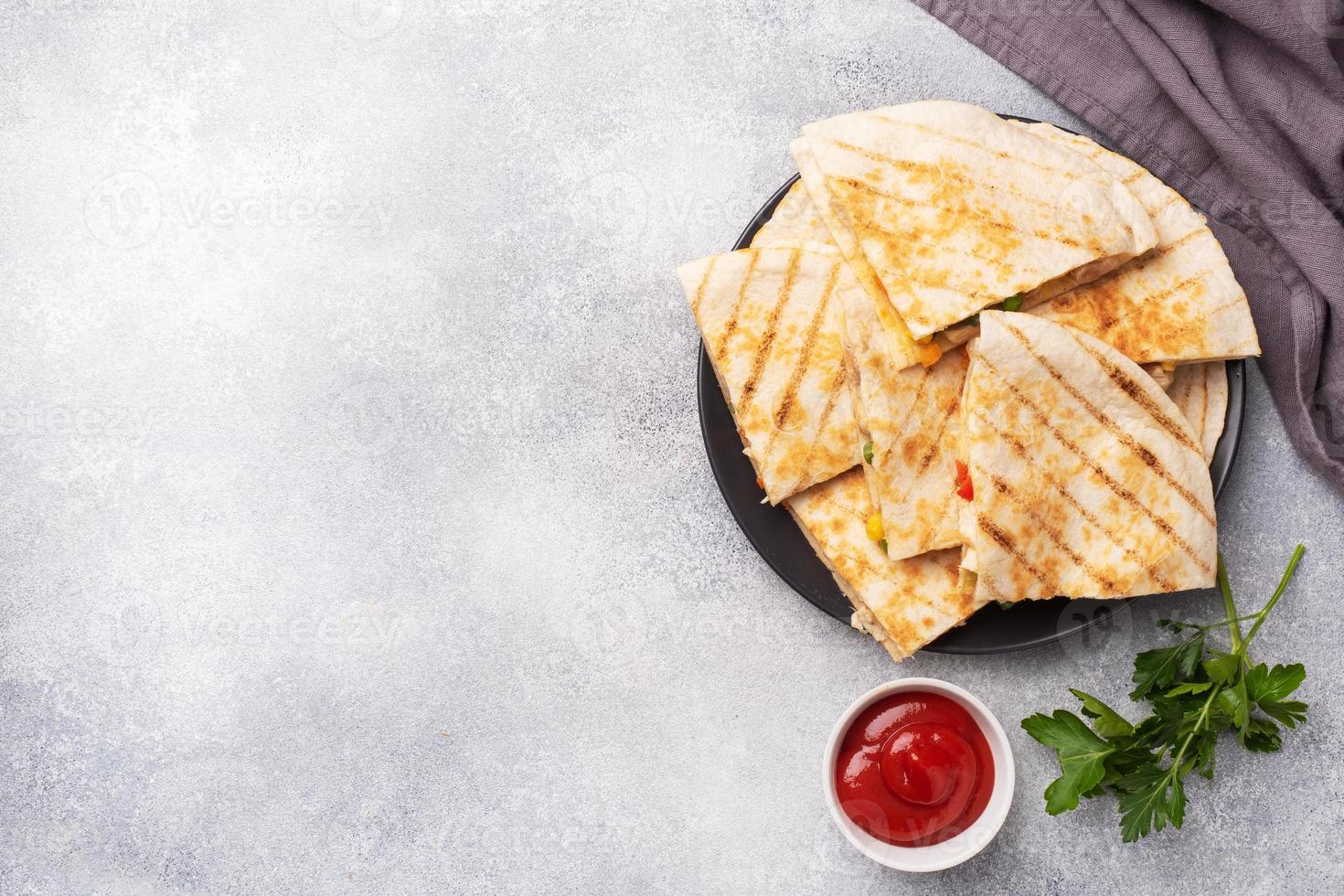 rebanadas triangulares de una quesadilla mexicana con la salsa. el platillo tradicional de mexico son las tortillas rellenas de carne y vegetales. copie el espacio foto