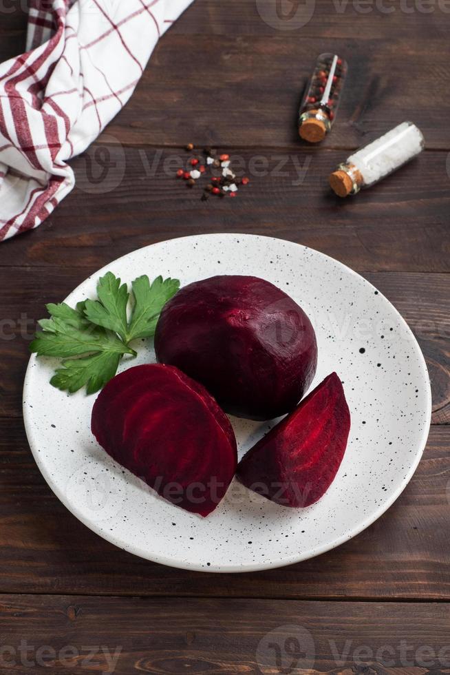 Boiled beets whole and cut on a cutting Board with parsley leaves on a wooden background. Copy space. photo