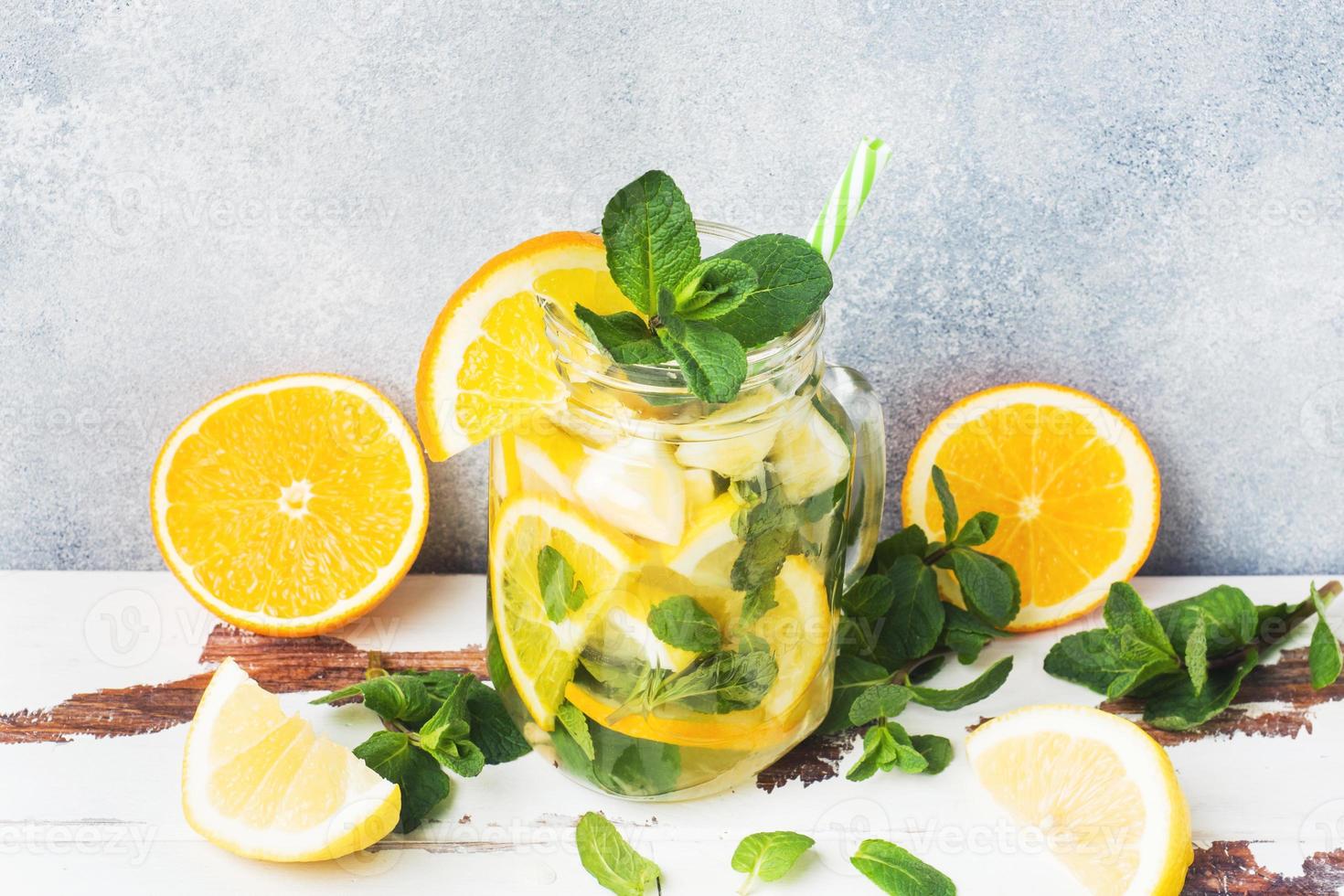 Lemonade drink of soda water, lemon and mint leaves in jar on light background. Copy space photo