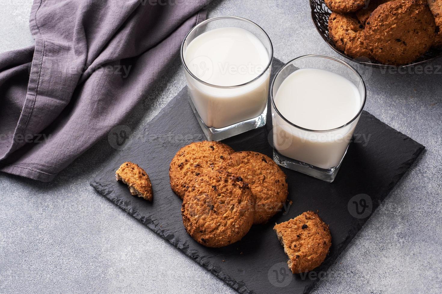 Homemade cookies cereals oats and a glass of milk on the grey concrete table. Copy space. photo