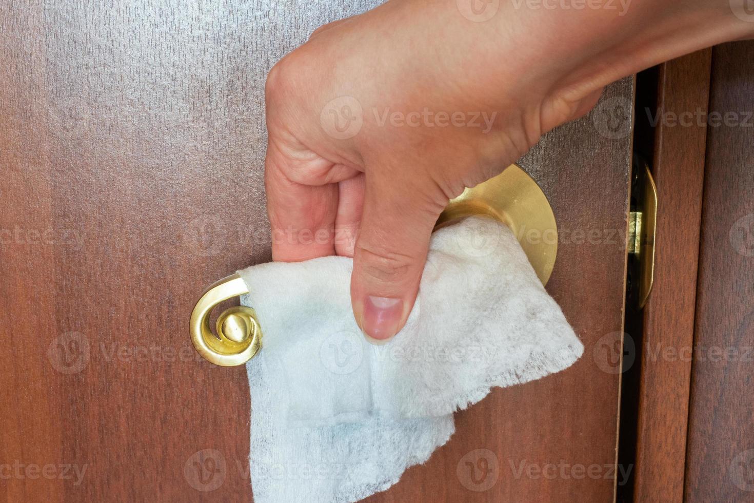 woman cleans the door handle with a napkin. Disinfection of surface microbes and viruses. photo