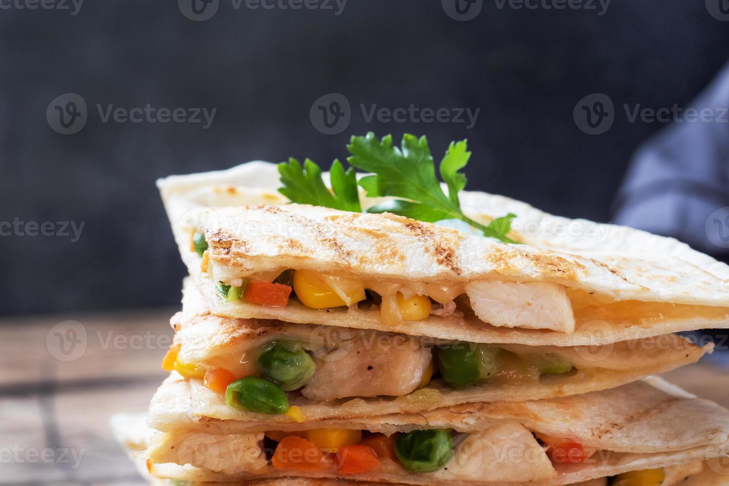 Triangular slices of a Mexican quesadilla with the sauce. The traditional dish of Mexico is tortillas stuffed with meat and vegetables. copy space. photo