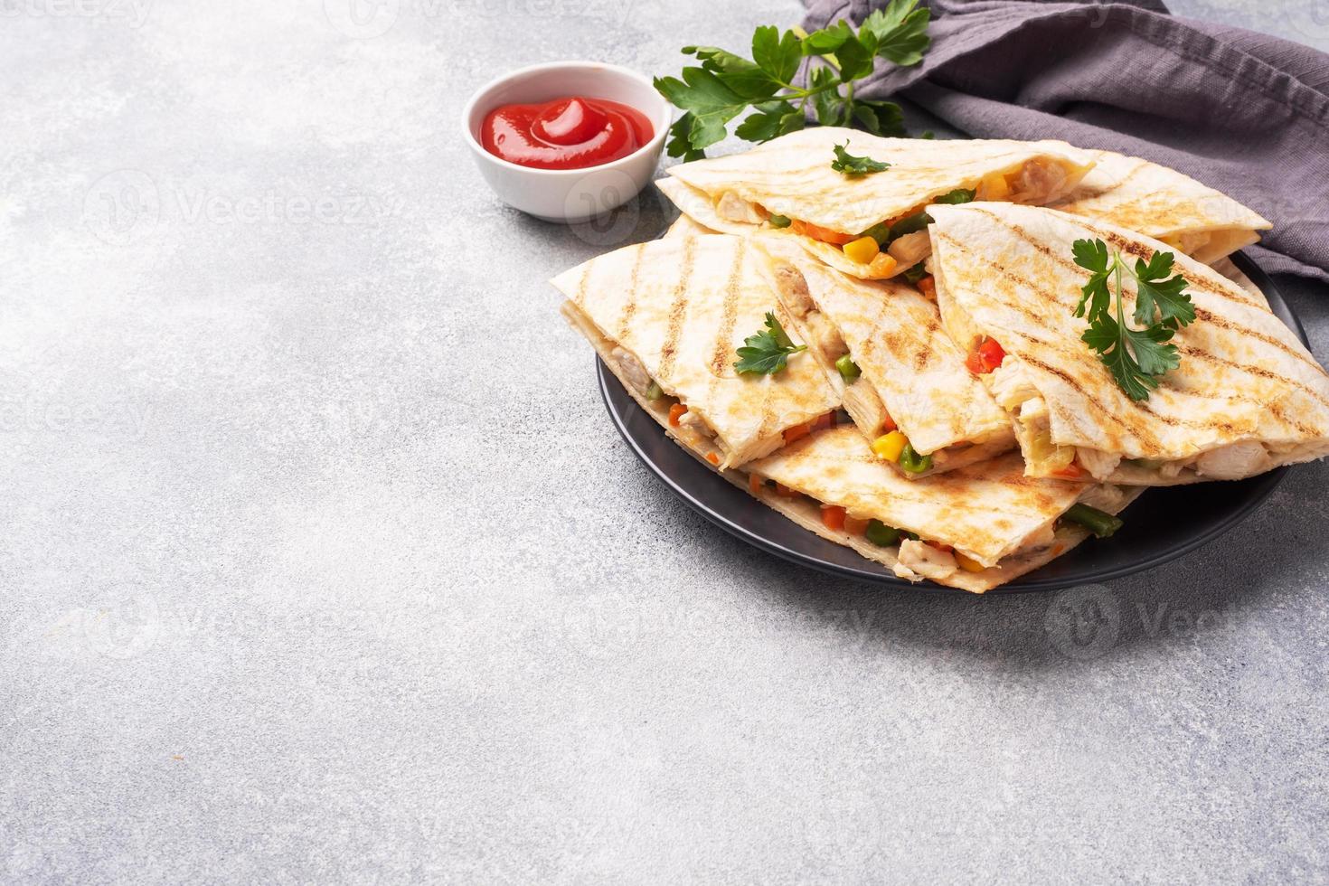 Triangular slices of a Mexican quesadilla with the sauce. The traditional dish of Mexico is tortillas stuffed with meat and vegetables. copy space. photo