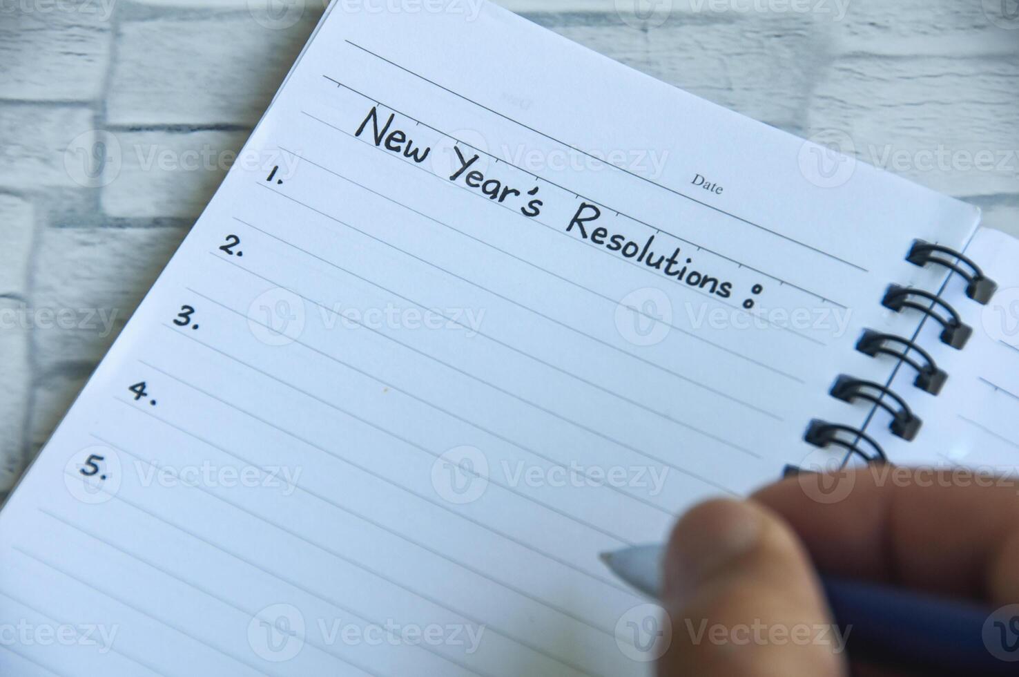 Hand writing New Year's Resolutions text on notepad. New beginning concept photo