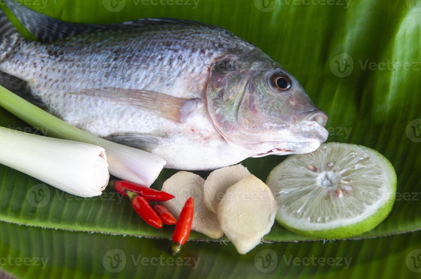 To view of fresh tilapia fish with lemongrass, lemon and chili on banana leaf. photo