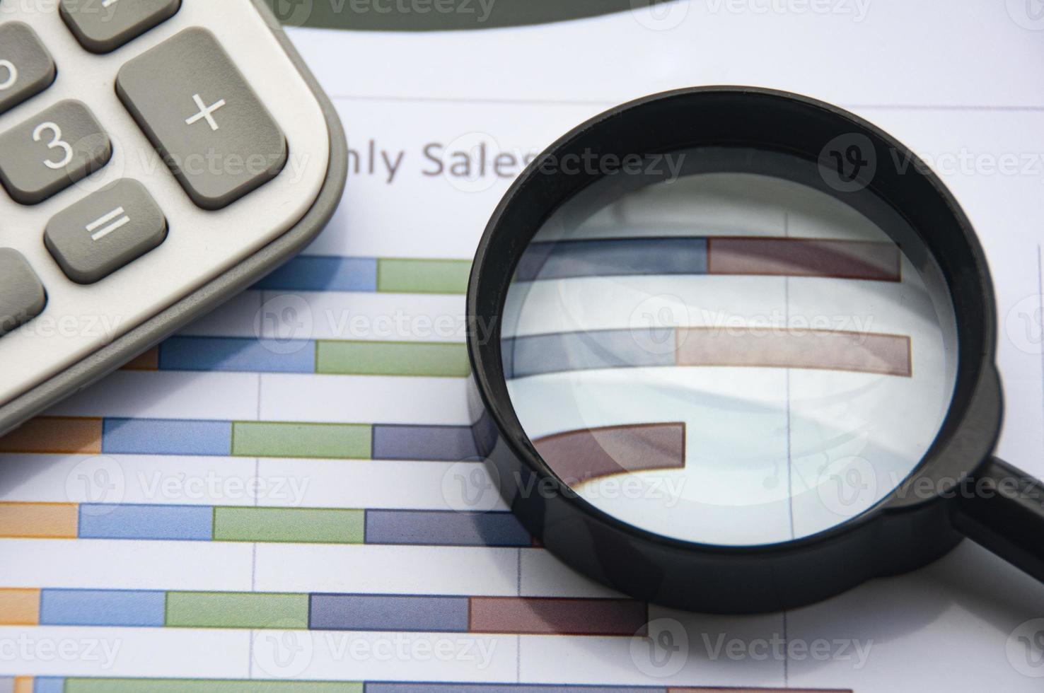 Analysis of data, chart and graphs with calculator and magnifying glass. Business finances concept photo