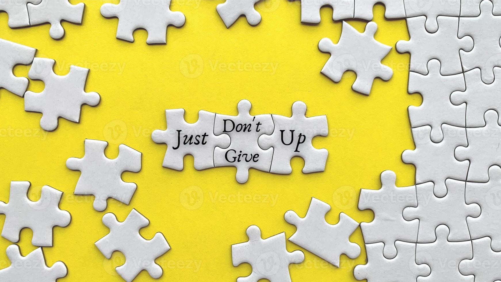 Top view of motivational quote on yellow cover - Just do not give up with jigsaw puzzle missing pieces background. photo