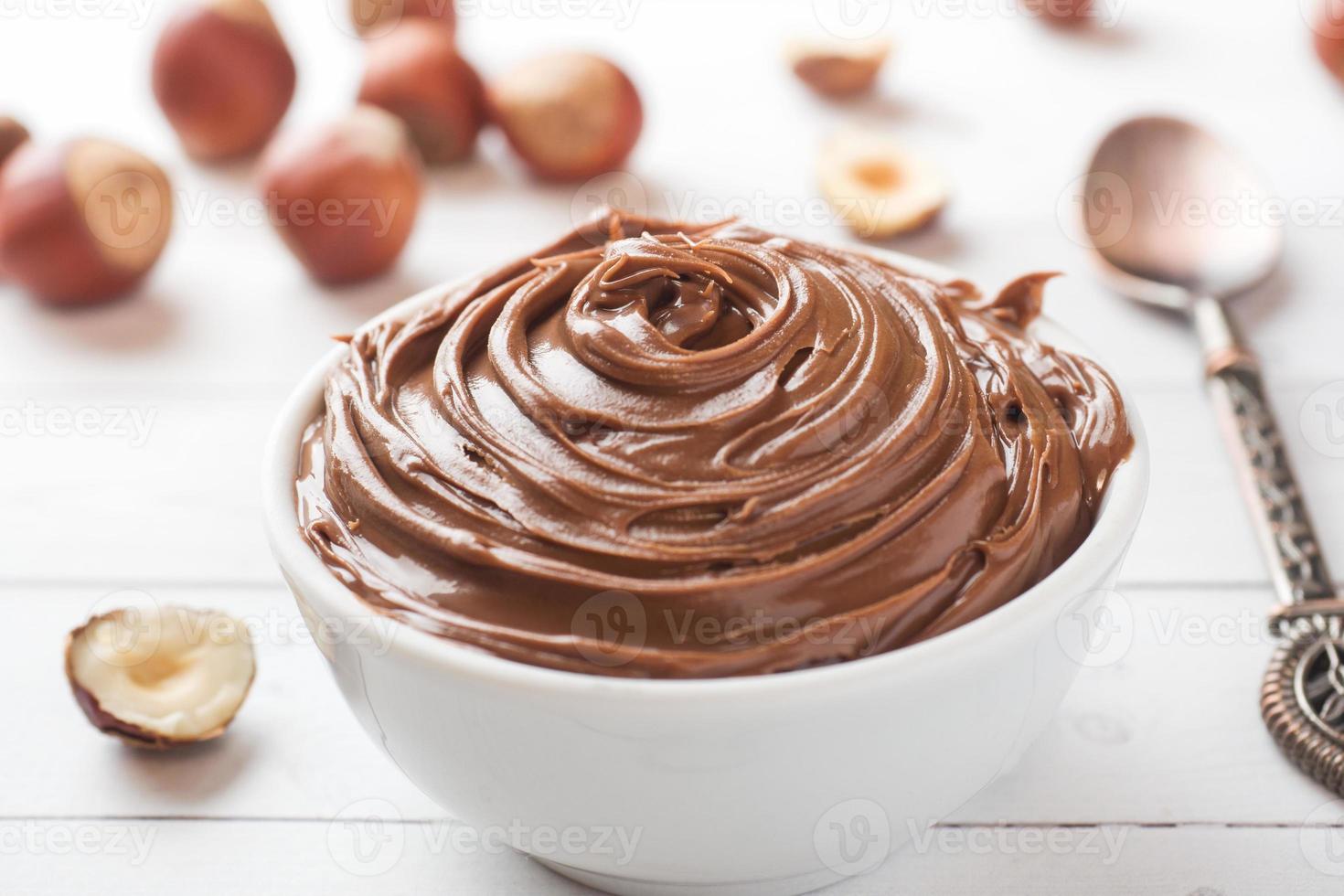 Nougat nut chocolate in a plate on a white background with hazelnut nuts. Concept of Breakfast. photo