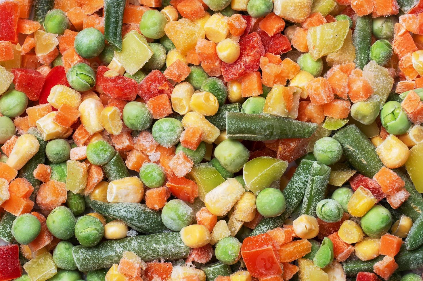 Chopped frozen vegetables background. Corn peas pepper carrots photo