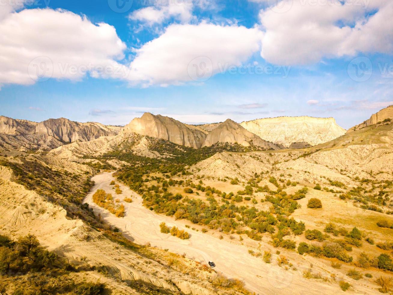 Aerial scenic view of Vashlovani national park protected area landscape with jeep on the road passing in the foreground photo