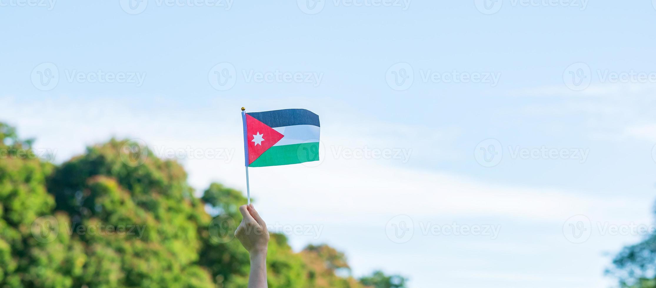 hand holding Jordan flag on nature background. Jordan Independence day and happy celebration concepts photo