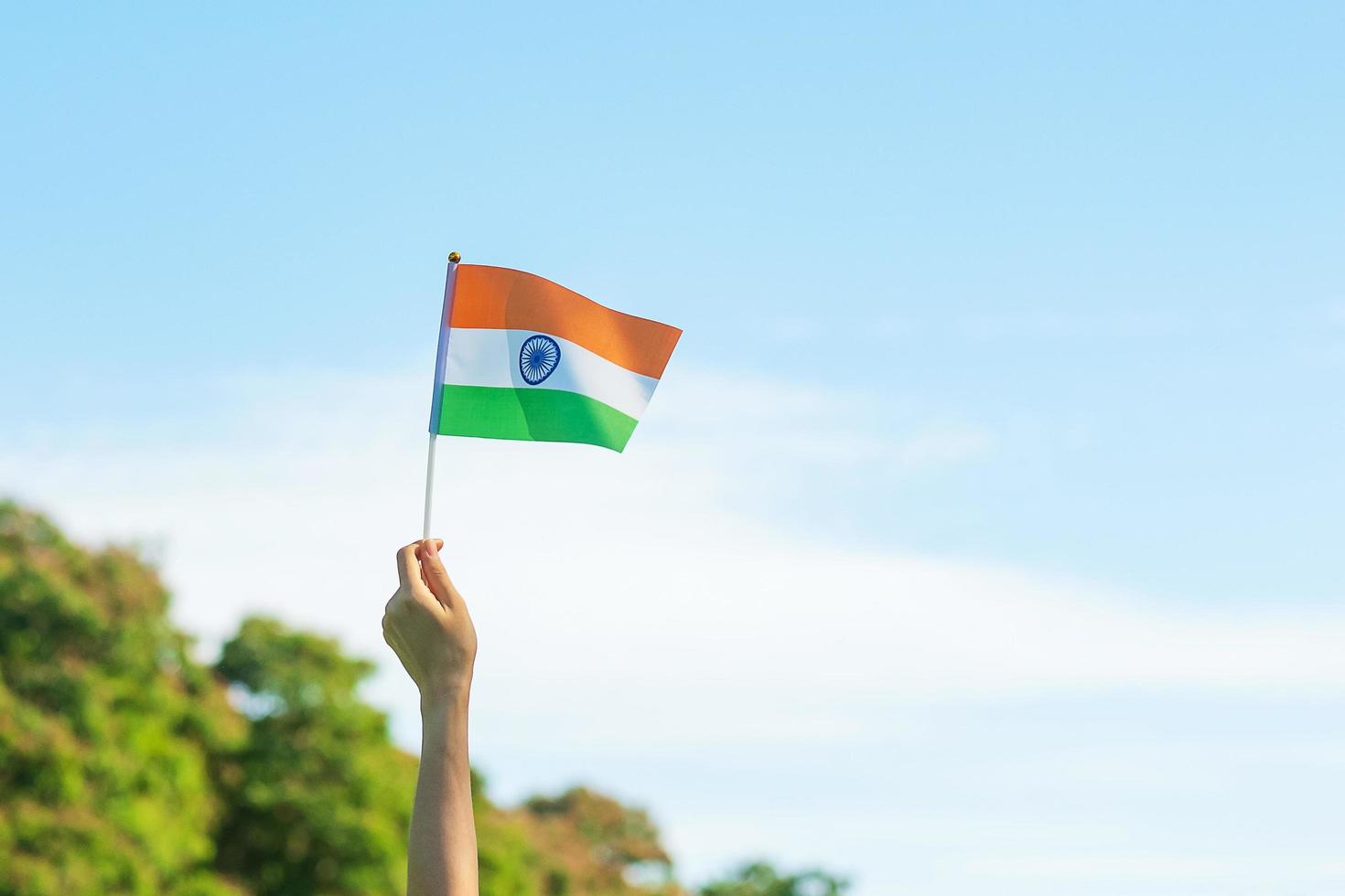 hand holding India flag on blue sky background. Holiday of India republic Day, happy Independence day and Gandhi Jayanti concepts photo