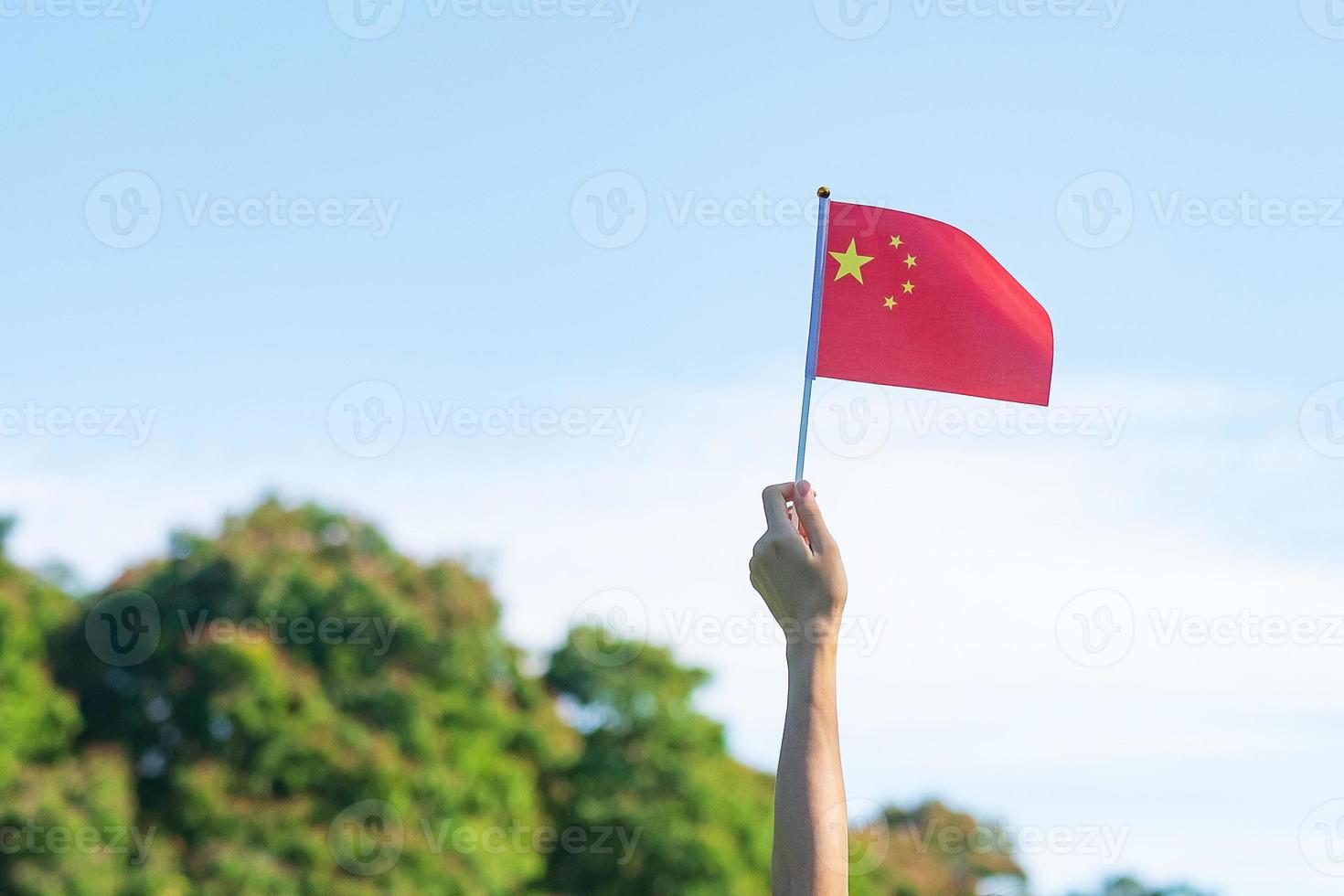 mano que sostiene la bandera china sobre fondo de cielo azul. día nacional de la república popular de china, día festivo de la nación pública y conceptos de celebración feliz foto