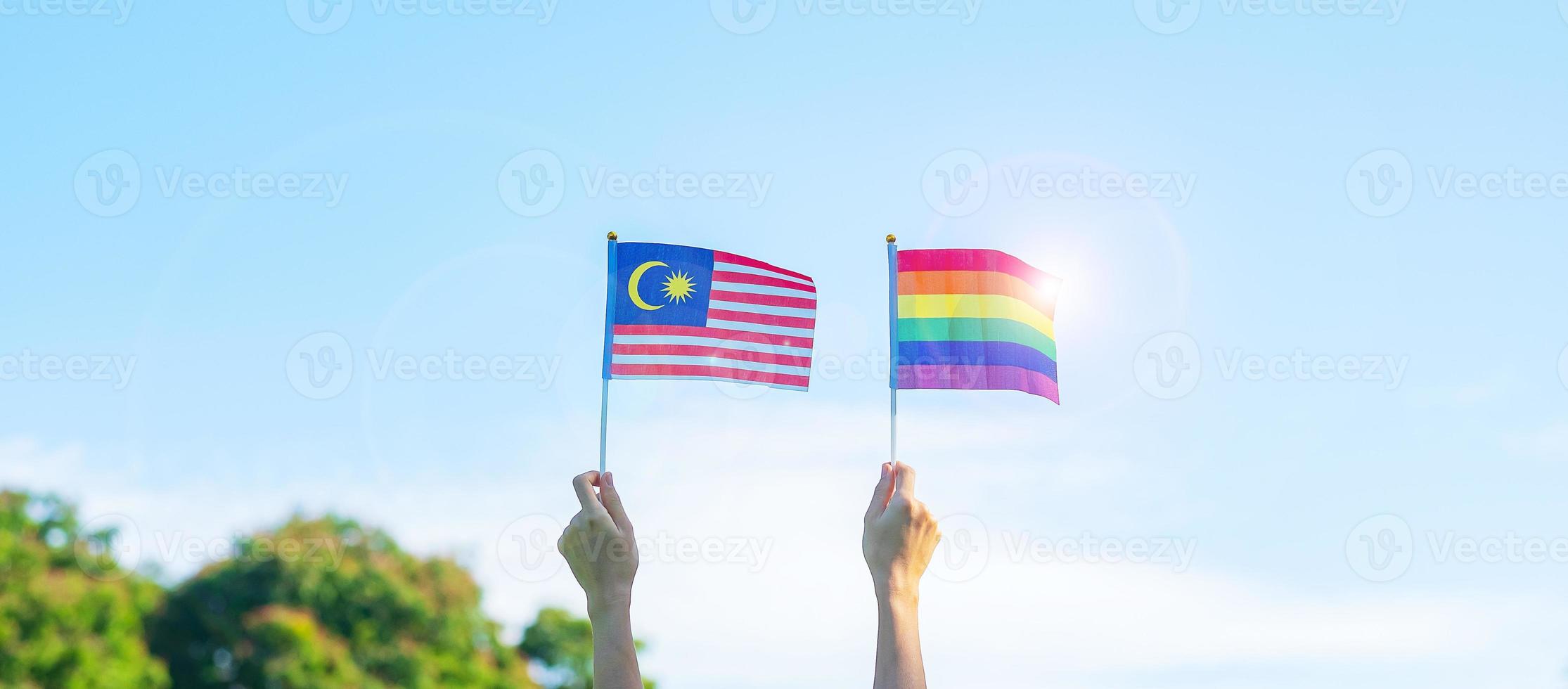hands showing LGBTQ Rainbow and Malaysia flag on nature background. Support Lesbian, Gay, Bisexual, Transgender and Queer community and Pride month concept photo