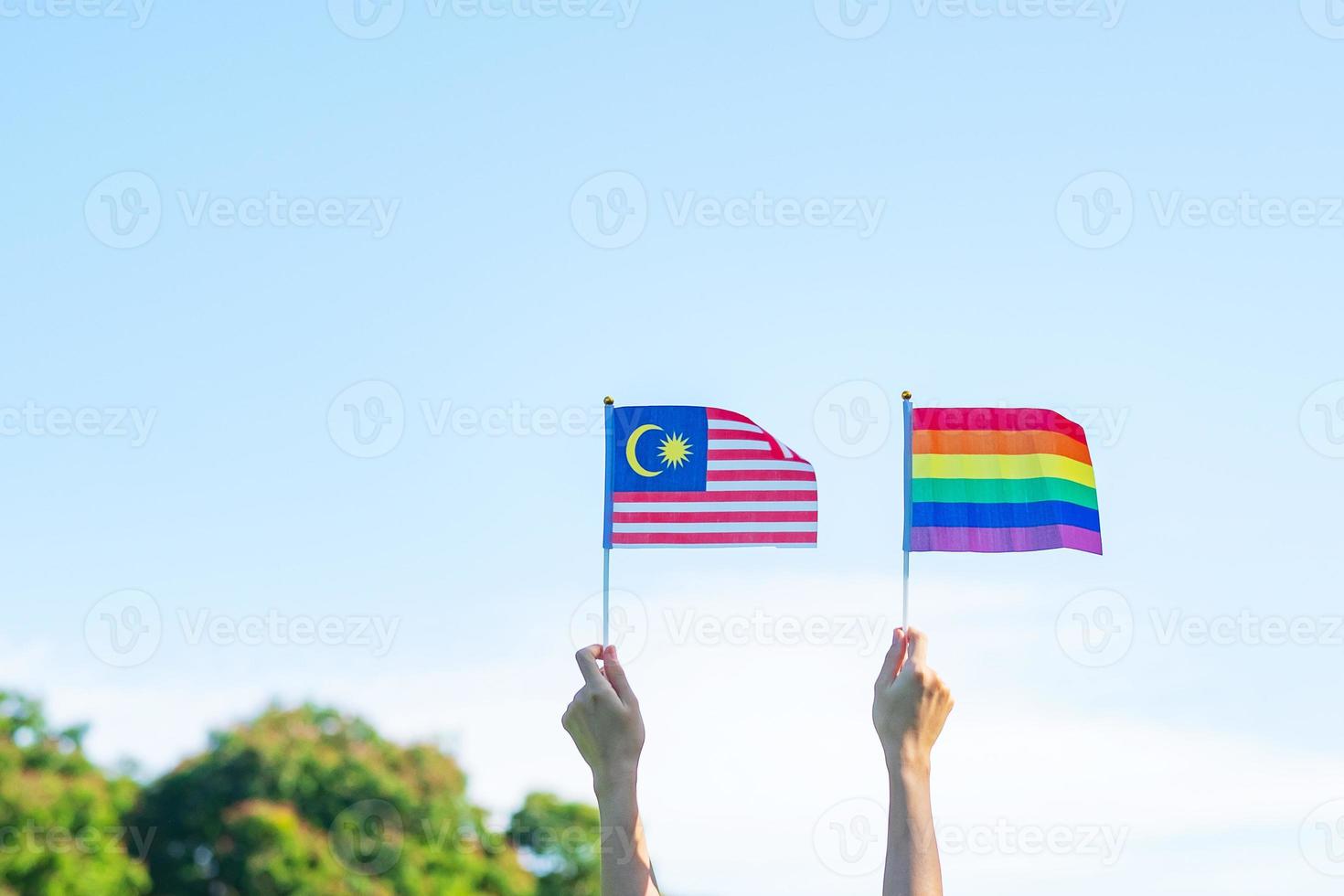hands showing LGBTQ Rainbow and Malaysia flag on nature background. Support Lesbian, Gay, Bisexual, Transgender and Queer community and Pride month concept photo