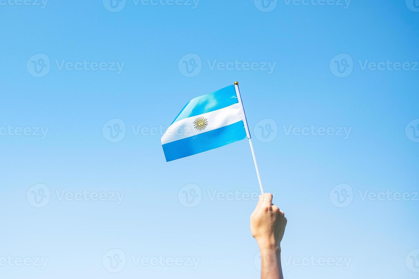 mano sosteniendo la bandera argentina en el fondo de la naturaleza. 9 de julio del día de la independencia, 25 de mayo del día de la revolución y conceptos de celebración feliz foto