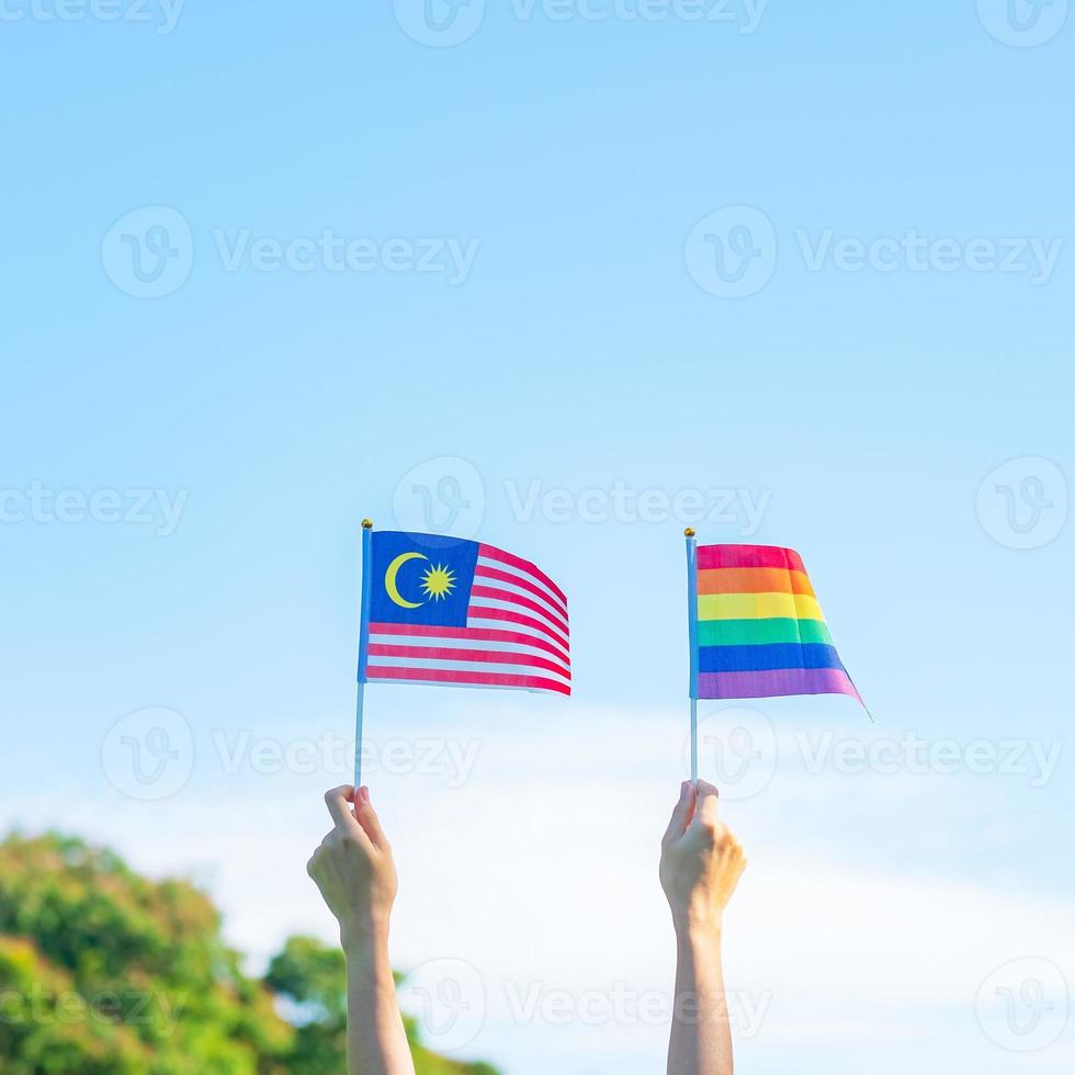 hands showing LGBTQ Rainbow and Malaysia flag on nature background. Support Lesbian, Gay, Bisexual, Transgender and Queer community and Pride month concept photo