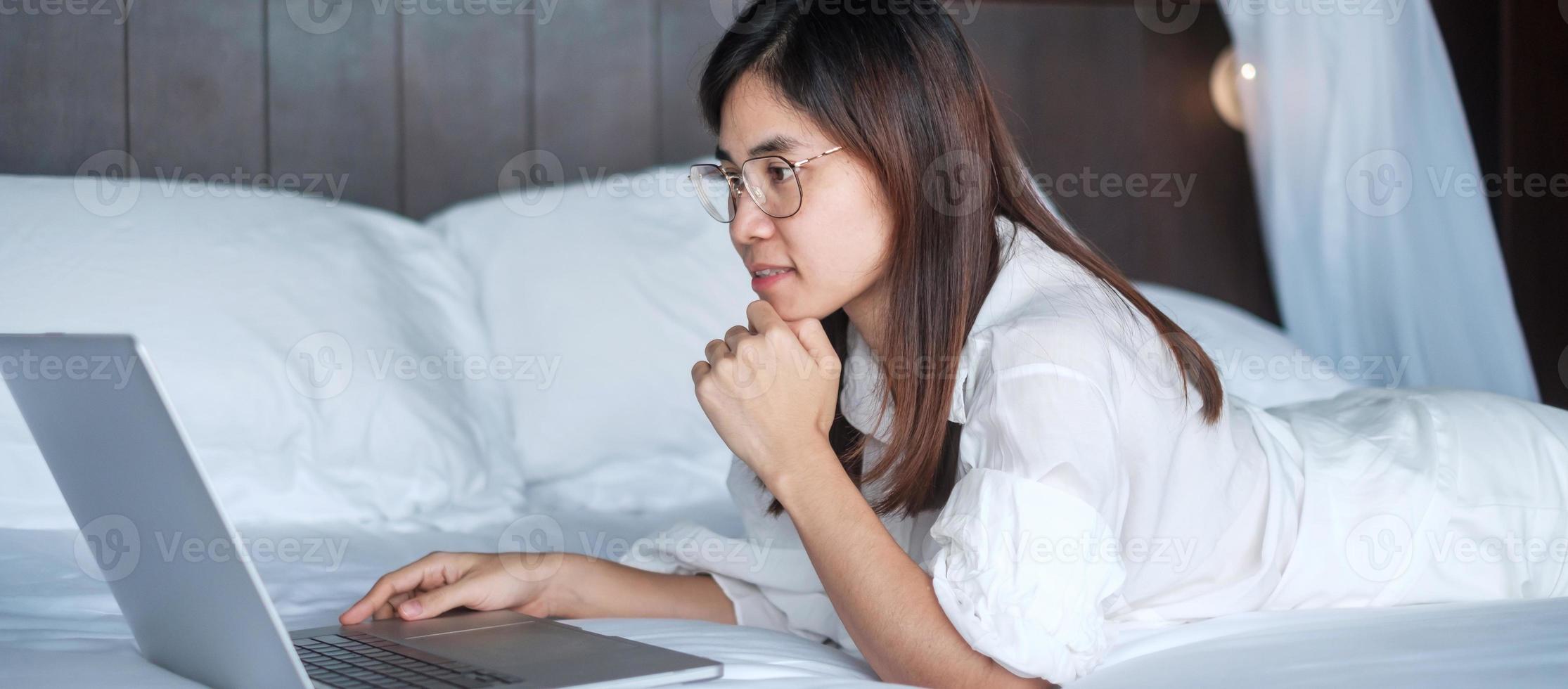 Happy woman using laptop for work, female meeting  online by computer notebook on bed. technology, network, work from home, lifestyle and digital communication concept photo