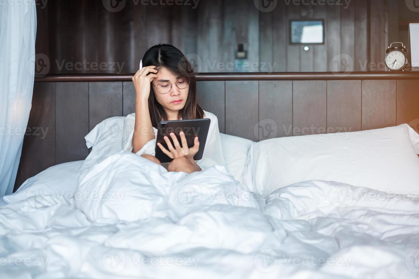 Happy woman using tablet for social media, young female watching movies on computer pad on bed at home. technology, network, online shopping, e commerce, lifestyle and digital communication concept photo