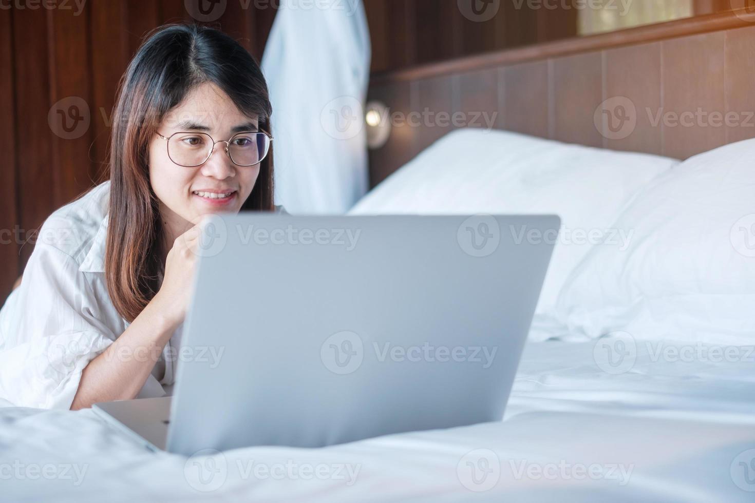 Happy woman using laptop for work, female meeting  online by computer notebook on bed. technology, network, work from home, lifestyle and digital communication concept photo