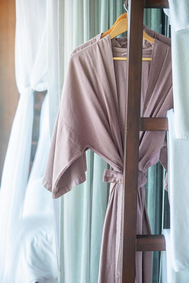 primer plano albornoz limpio y toalla colgada en un armario de madera en un hotel de lujo. relajarse y viajar concepto foto