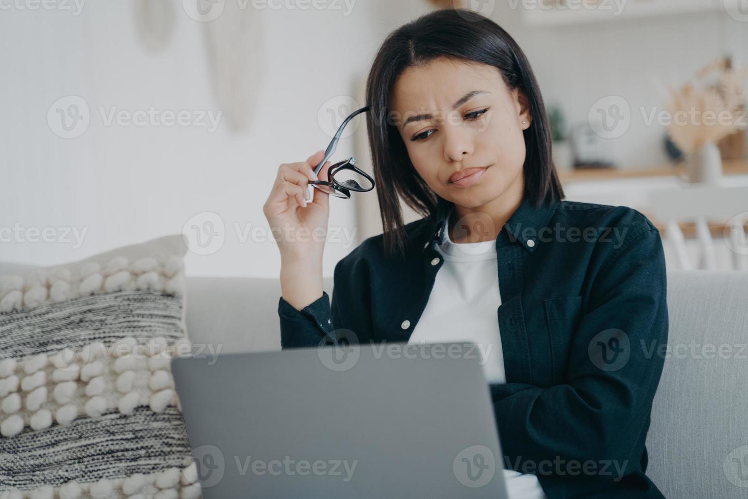 Focused businesswoman frowning works on business project at laptop at home. Stress at work, overtime photo