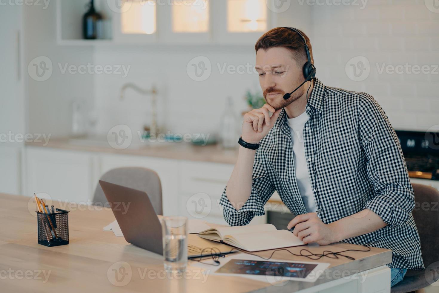 Smiling young man listening attentively to lecture online at home photo