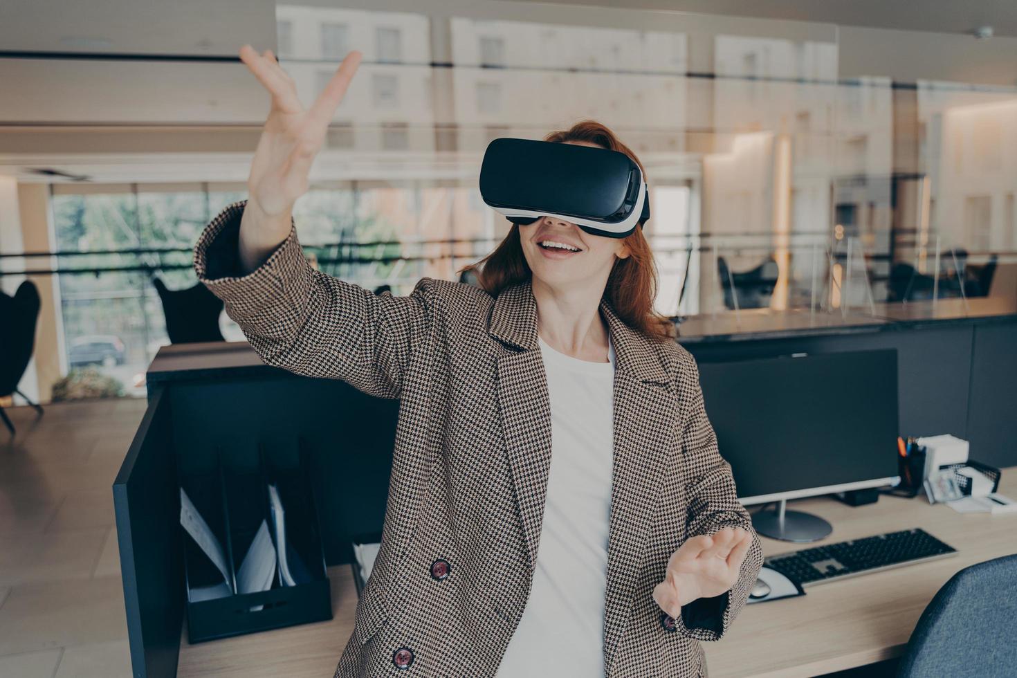 Female office worker using virtual reality headset to visualize and browse files at work photo