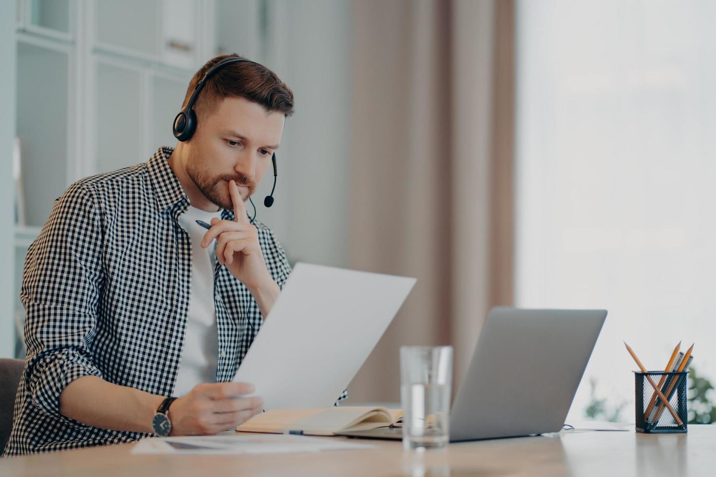 Concentrated man reading document and working at home photo