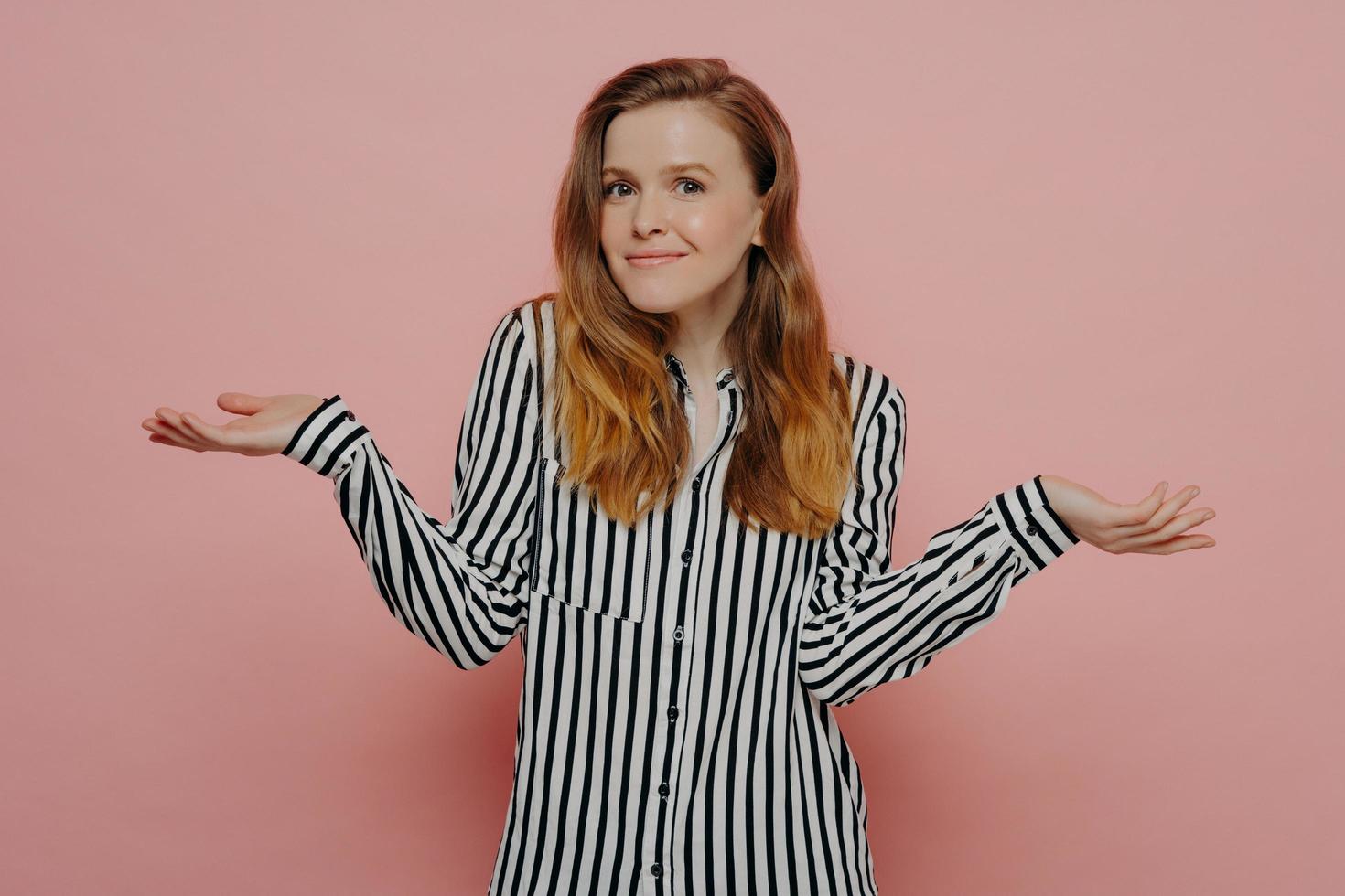 Brunette woman with long hair in striped shirt shrugging shoulders photo