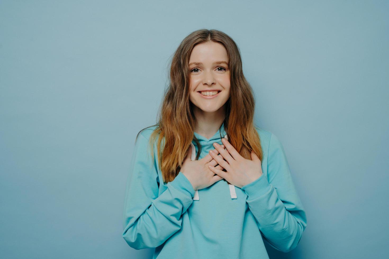 Young woman holding hands on chest and expressing happiness and gratitude photo