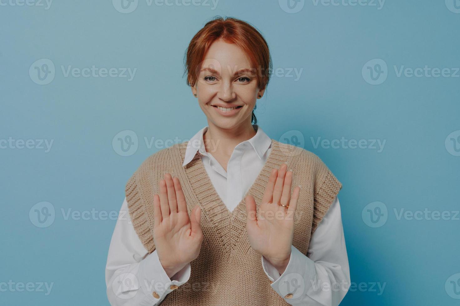 Positive young 30s red haired woman saying no while standing isolated on blue wall background photo