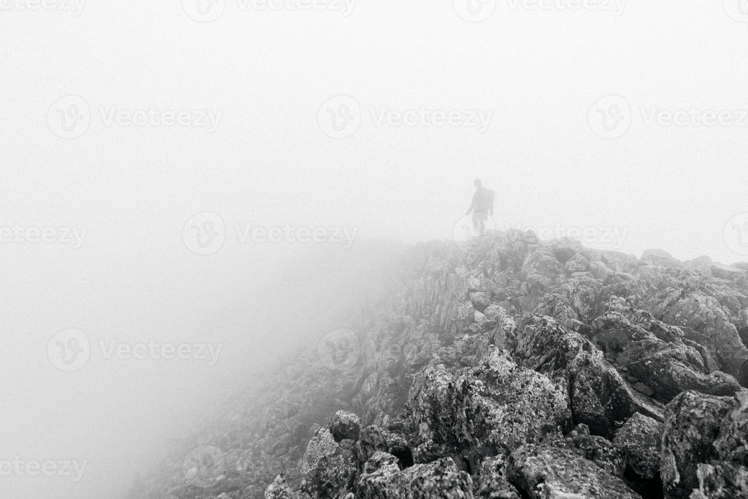 Black and white hiker on a foggy mountain photo