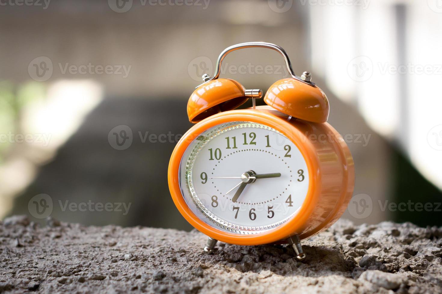 Orange vintage style alarm clock in an abandoned unfinished building. photo