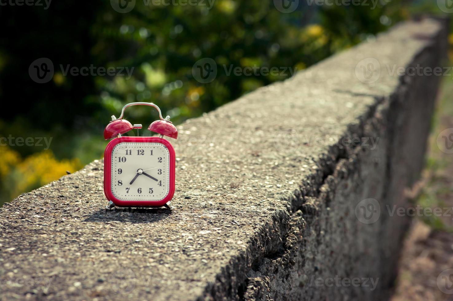 Red vintage style analog alarm clock on a concrete surface. photo