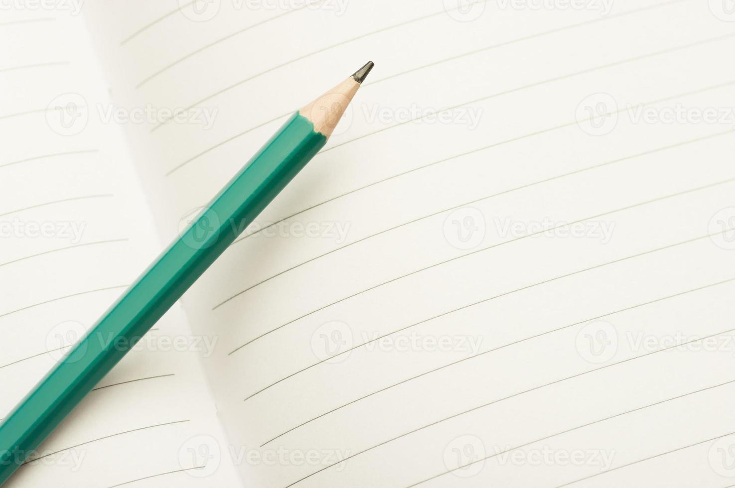 Green pencil on an open notebook. Minimal education concept layout with a pencil. photo