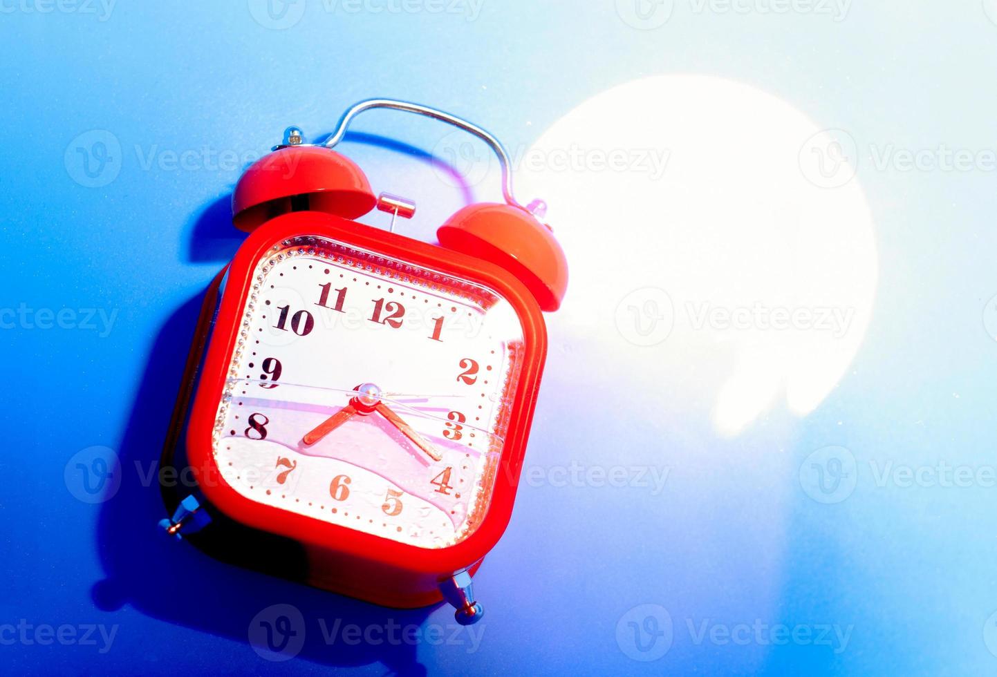 Red retro style analog alarm clock uner the bright light. photo